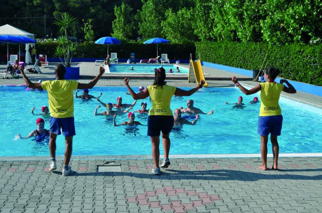 Tre istruttori guidano attività di fitness in piscina.