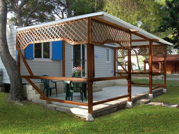 Casa mobile con veranda in legno e tavolo fuori.