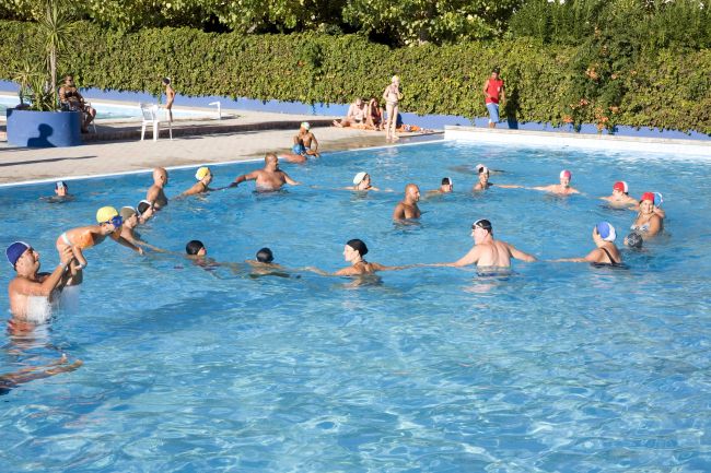 Gruppo di persone nuota in una piscina all'aperto.