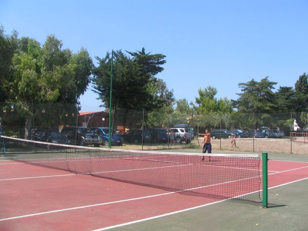 Campo da tennis all'aperto con rete e persone in gioco.