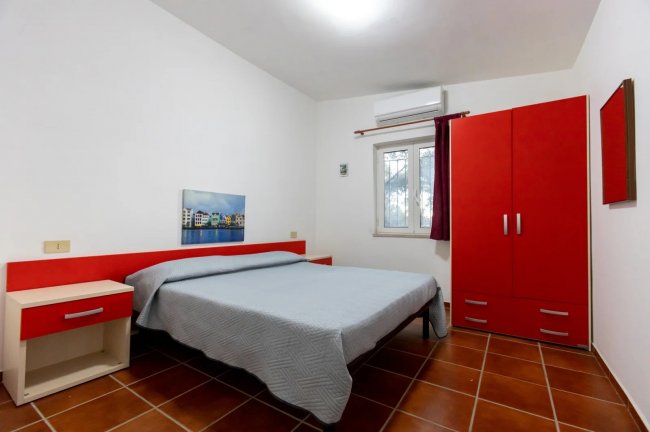 Camera con mobili rossi e pavimento marrone.