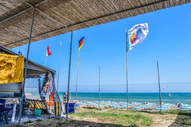 Spiaggia con bandiere e ombrelloni vicino al mare.