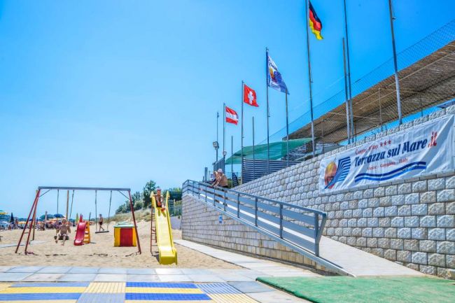 Scivolo e altalene su una spiaggia sabbiosa.