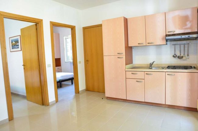 Cucina con mobili in legno e due porte a vista.